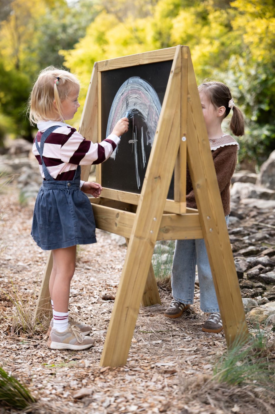 Two children drawing with chalk on the Classic Outdoor timber chalkboard easel