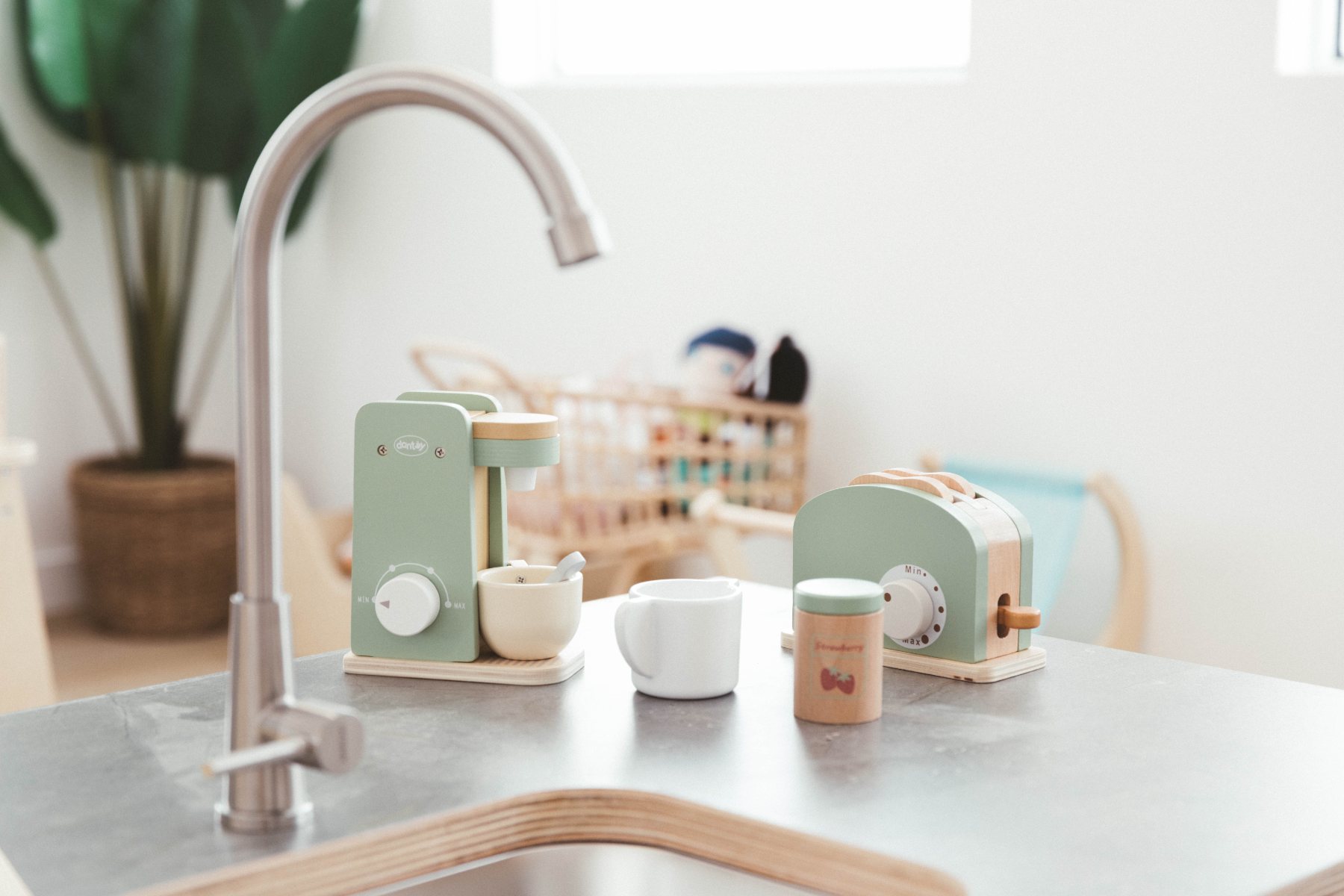 Wooden play coffee maker and toaster on a play kitchen bench
