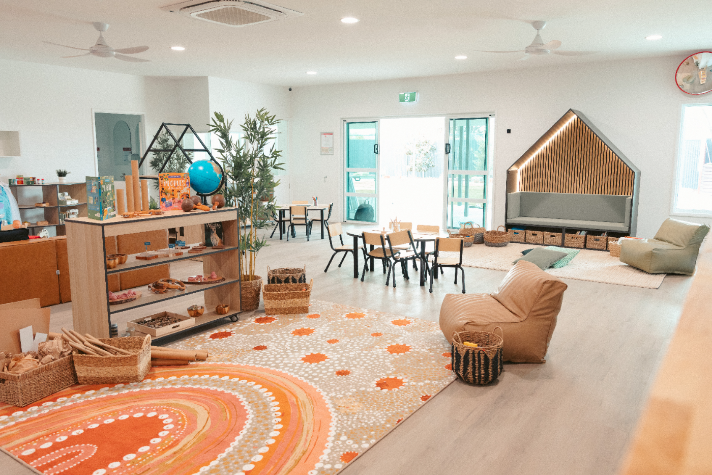 Open-plan Step4 centre room with timber shelving, house-shaped reading nook and rugs