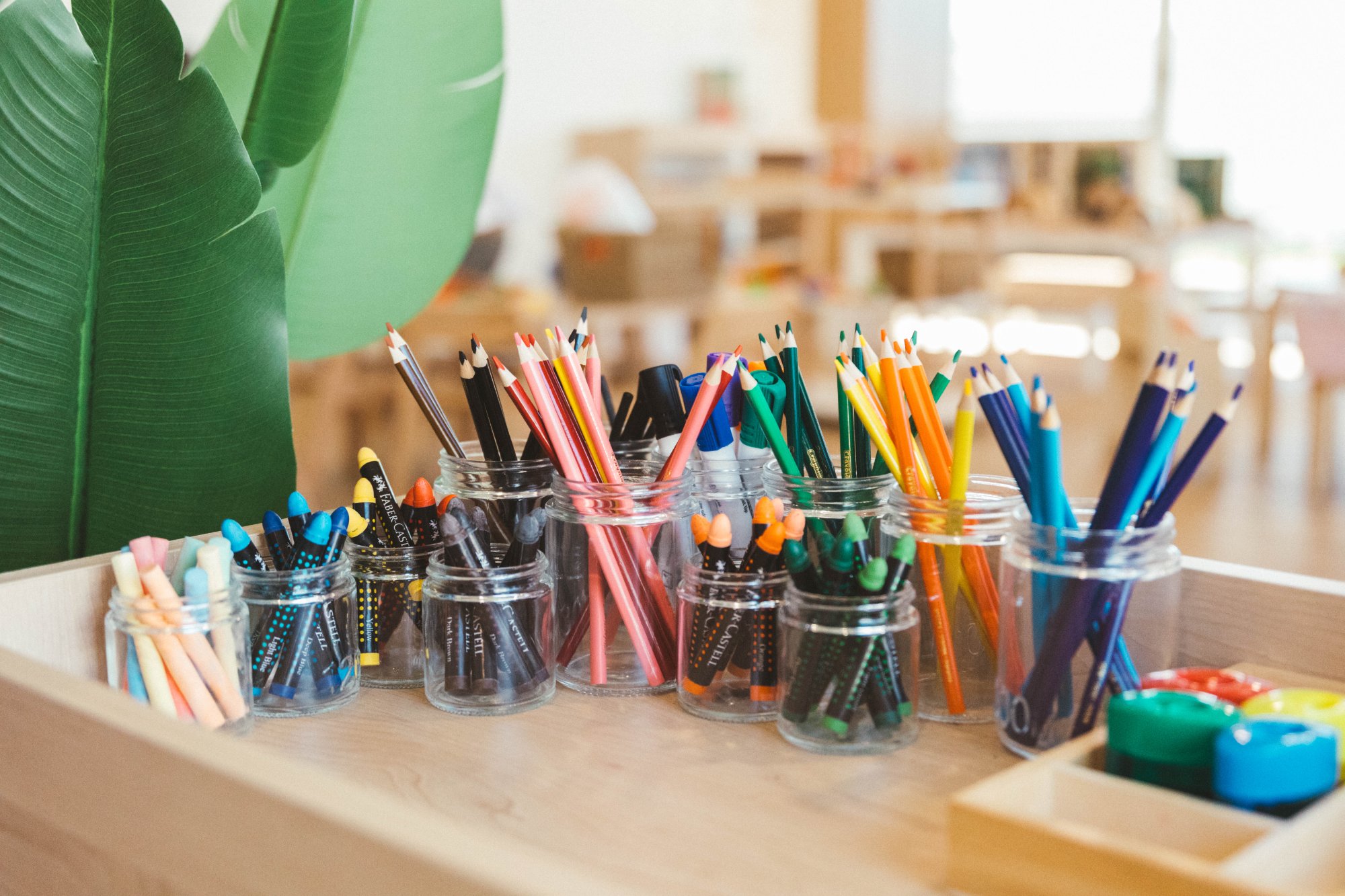 Jars of coloured pencils, crayons and chalk on a timber art trolley