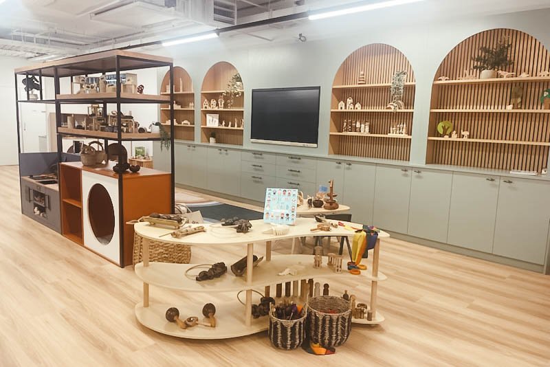 The Step4 showroom with arched timber display shelving, curved resource tables and a styled play unit